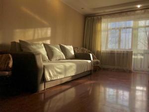 a living room with a couch and a window at City Center Apartment in Karagandy