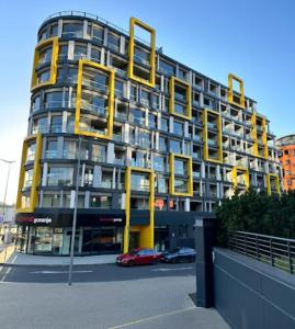 布拉格的住宿－O2 Arena Holliday suites，一座高大的黄色建筑,前面有汽车停放