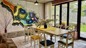 ein Esszimmer mit einem Tisch, Stühlen und einem Wandbild in der Unterkunft Paradiso Hotel in Telawi + 14 Fotos