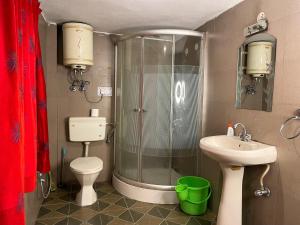 un bagno con doccia, WC e lavandino di Aarya homes a Manāli