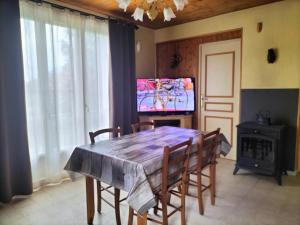 een eetkamer met een tafel met stoelen en een televisie bij Maison avec jardin de 600 m2 au cœur des cévennes in Sénéchas