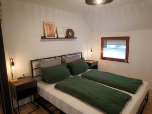 a bedroom with a bed with green sheets and a window at Fuchsbau in Schleiden