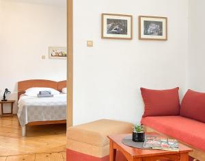 a living room with a red couch and a bed at TerraMar Apartments in Baška Voda