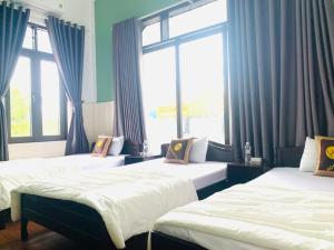 dwa łóżka w pokoju z dwoma oknami w obiekcie Hoa Mai Hotel w mieście Dong Hoi
