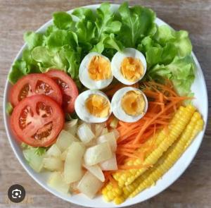 a plate of food with eggs and lettuce and vegetables at YOK GUEST HOSE (JOMTIEN) HOSTEL in Jomtien Beach