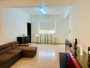 ein Wohnzimmer mit einem braunen Sofa und einem Bildschirm in der Unterkunft 2 bedroom 2 bathroom Apartment in Sliema