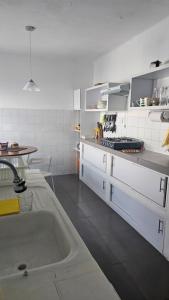 een keuken met witte kasten en een wastafel bij Casa de Playa Tortugas Casma, Habitación 4 a 6 personas con 1 baño in Tortuga
