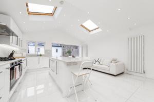 eine weiße Küche mit einem Tisch und einem Sofa in der Unterkunft Spot Homes Guest House in London