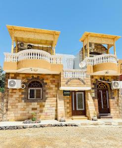 Abu simbel Nubian Guest House في أبو سمبل: منزل من الطوب مع شرفتين فوقه