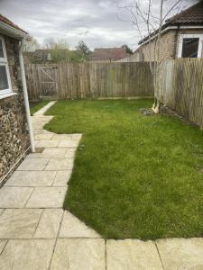 a yard with a fence and green grass at Charming 3 bedroom flint cottage in Lakenheath