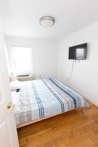 a white bedroom with a bed and a flat screen tv at Pristine 2-Bed Apt with Skyline Views - mins to NYC in Union City