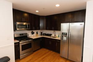 a kitchen with stainless steel appliances and wooden cabinets at Pristine 2-Bed Apt with Skyline Views - mins to NYC in Union City