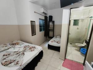 um pequeno quarto com 2 camas e um chuveiro em Hotel Mãe Rainha em Aparecida