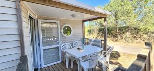 a patio with a table and chairs on a porch at Mobil home 4 pers ombragé climatisé camping Marvilla parc AGDE in Agde