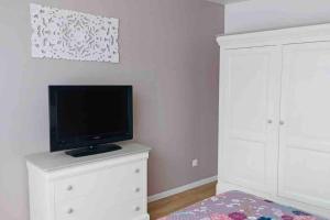 een woonkamer met een tv op een wit dressoir bij La Margautine, la mer à proximité. in Sangatte