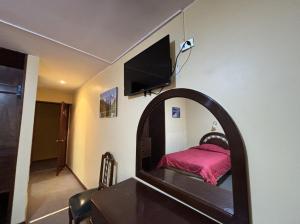 ein Schlafzimmer mit einem Spiegel, einem Bett und einem TV in der Unterkunft Hotel Los Portales in Huaraz