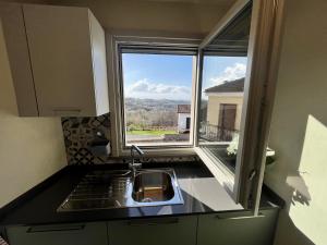 a kitchen with a sink and a large window at La Casa di Margot - Alloggio Blu in Murazzano