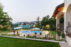 a backyard with a pool with chairs and umbrellas at Vila Sarajevo in Sarajevo