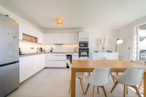 eine Küche mit einem Holztisch und weißen Schränken in der Unterkunft Le Rooftop de la Peyrière - Parking - Climatisation - 10 min de Montpellier in Saint-Jean-de-Védas
