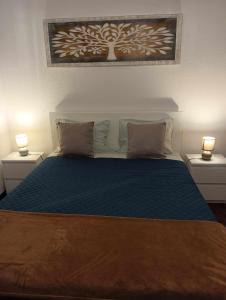 a bedroom with a blue bed with two night stands at Maresia's House in Madalena do Mar