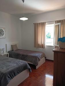 1 dormitorio con 2 camas y ventana en Maresia's House, en Madalena do Mar