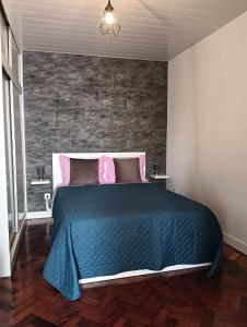 1 dormitorio con 1 cama con manta azul y almohadas rosas en Maresia's House en Madalena do Mar