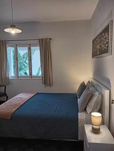 Un dormitorio con una cama azul y una ventana en Maresia's House, en Madalena do Mar