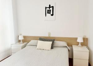 a white bedroom with a bed and two lamps at ACOGEDOR PISO EN CULLERA JUNTO AL MAR in Cullera