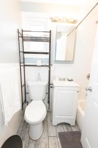 La salle de bains est pourvue de toilettes, d'un lavabo et d'un miroir. dans l'établissement Cozy & Classy 3-Bed to mins NYC, à Jersey City