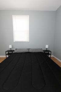 a bedroom with a large black bed with two tables at Cozy & Classy 3-Bed to mins NYC in Jersey City