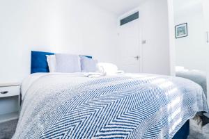 een slaapkamer met een bed met een blauw en wit dekbed bij Tranquil 3BR Retreat for Families in Bexleyheath in Bexleyheath