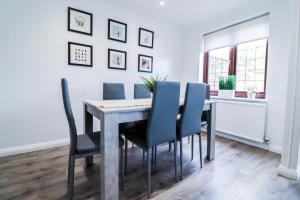 Tranquil 3BR Retreat for Families in Bexleyheath في بيكسليهيث: غرفة طعام مع طاولة وكراسي زرقاء