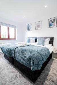 a bedroom with a large bed with a blue blanket at Tranquil 3BR Retreat for Families in Bexleyheath in Bexleyheath