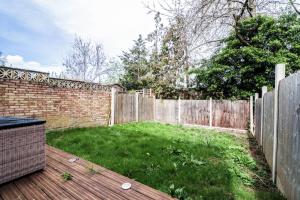 a backyard with a wooden fence and a green yard at Tranquil 3BR Retreat for Families in Bexleyheath in Bexleyheath