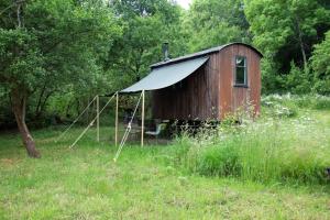 un viejo cobertizo sentado en medio de un campo en The shepherds hut at abberley glamping, en Abberley