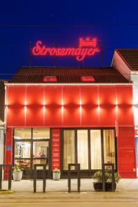a red store front with a neon sign on it at Pansion Strossmayer in Osijek