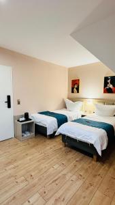 two beds in a room with wooden floors at Hotel Libers in Lauterbach