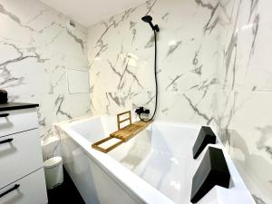 ein Badezimmer mit einer weißen Badewanne und Marmorwänden in der Unterkunft Baignoire Spa - 2 pièces moderne in Villeneuve-la-Garenne