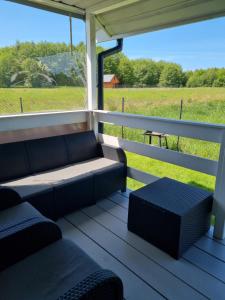 - une terrasse couverte avec des canapés et une vue sur un champ dans l'établissement domki letniskowe ŚWIĘTY SPOKÓJ, à Rusinowo