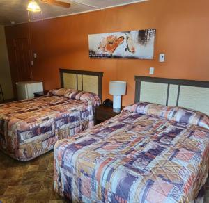 2 Betten in einem Hotelzimmer mit orangefarbenen Wänden in der Unterkunft Motel Au Soleil couchant in Rimouski