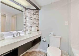 a bathroom with a toilet and a sink and a mirror at Tranquil Palms-Oceanfront Condo in Myrtle Beach