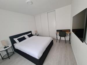 Schlafzimmer mit einem Bett, einem Schreibtisch und einem TV in der Unterkunft Baignoire Spa - 2 pièces moderne in Villeneuve-la-Garenne