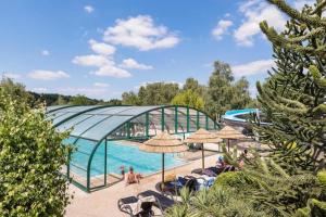 una piscina en un complejo con sombrillas y una piscina en Mobilhome 4 étoiles - Piscine - efadcg, en Vernioz