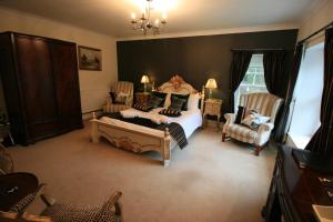 a bedroom with a bed and chairs and a chandelier at High Dalby House in Pickering