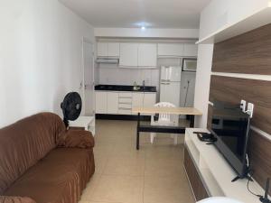 a living room with a couch and a kitchen at Novo apto com garagem no centro de Passo Fundo RS in Passo Fundo