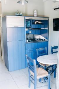a kitchen with blue cabinets and a table with chairs at Niriides Apartments in Kourouta