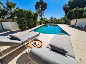 a swimming pool with two chaise lounges next to at Villa moderna de lujo de nueva construcción a 1km de Playa Fustera - Ref A014 AVANOA PREMIUM RENTALS in Benissa