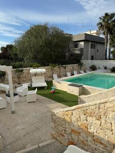 un patio trasero con piscina, sillas y mesa en CASA AL MARE LUXURY, en Bari
