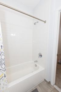 uma banheira branca numa casa de banho branca em Modern & Cozy 2 - Bedroom gem mins from NYC em Jersey City