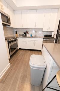 uma cozinha com armários brancos e uma lata de lixo em Modern & Cozy 2 - Bedroom gem mins from NYC em Jersey City